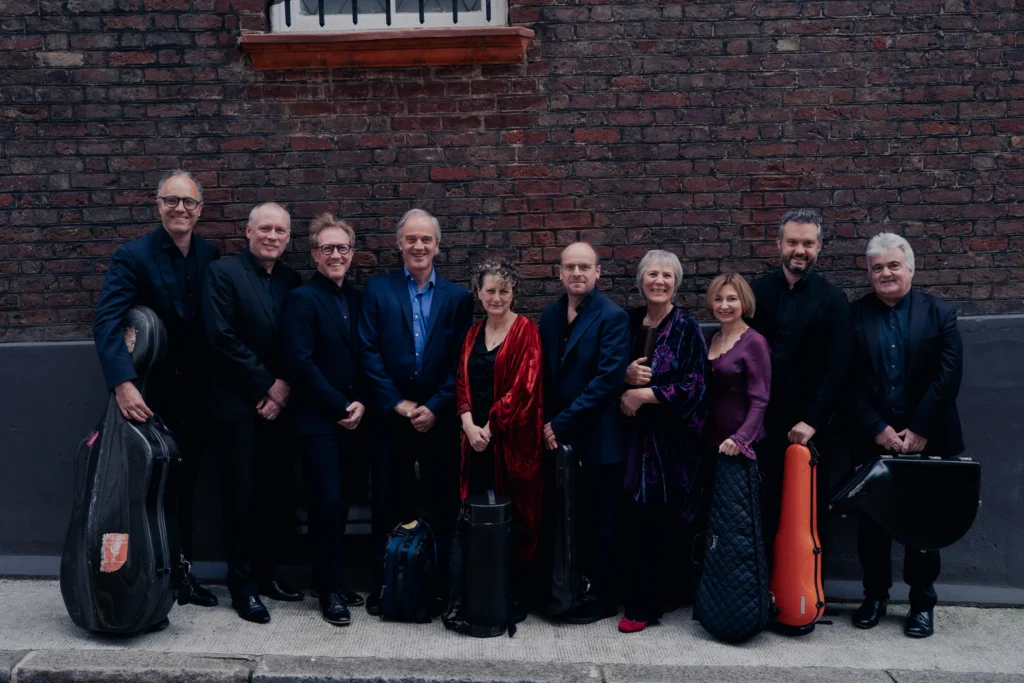 The Nash Ensemble standing in front of a wall together